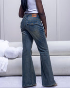 Person wearing blue jeans and a white shirt in a minimalistic room.